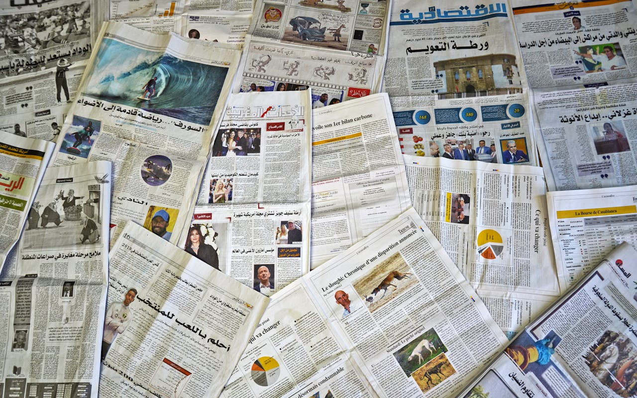 A variety of Arabic newspapers laid out, showcasing cultural and news diversity in Fès, Morocco.
